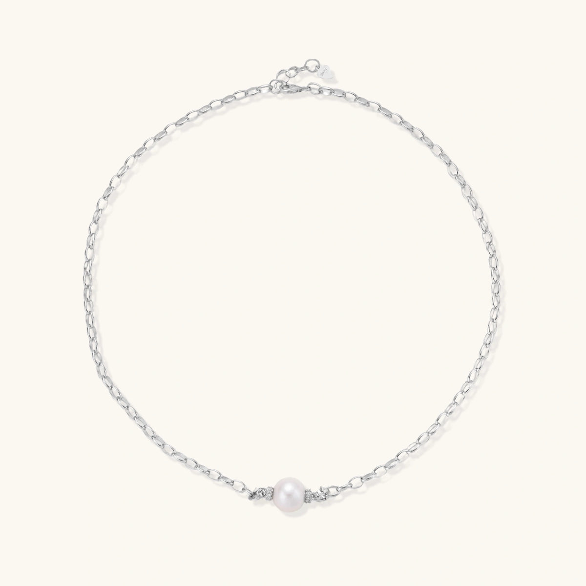 Dainty rhodium-plated silver chain necklace with centered 10mm freshwater pearl and crystal accents on cream background