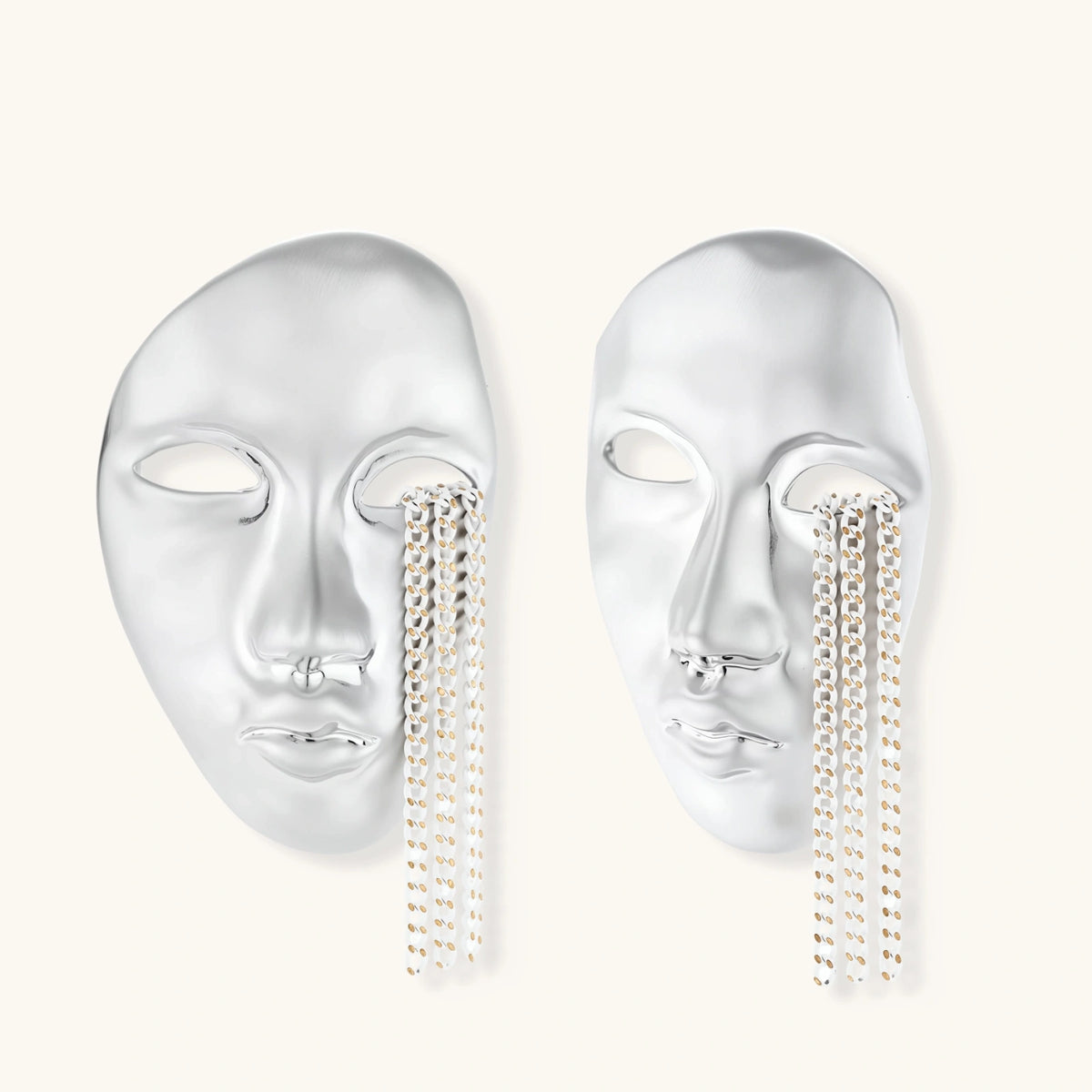 Silver face-shaped statement earrings with flowing chain tassels hanging from sculpted lips on cream background