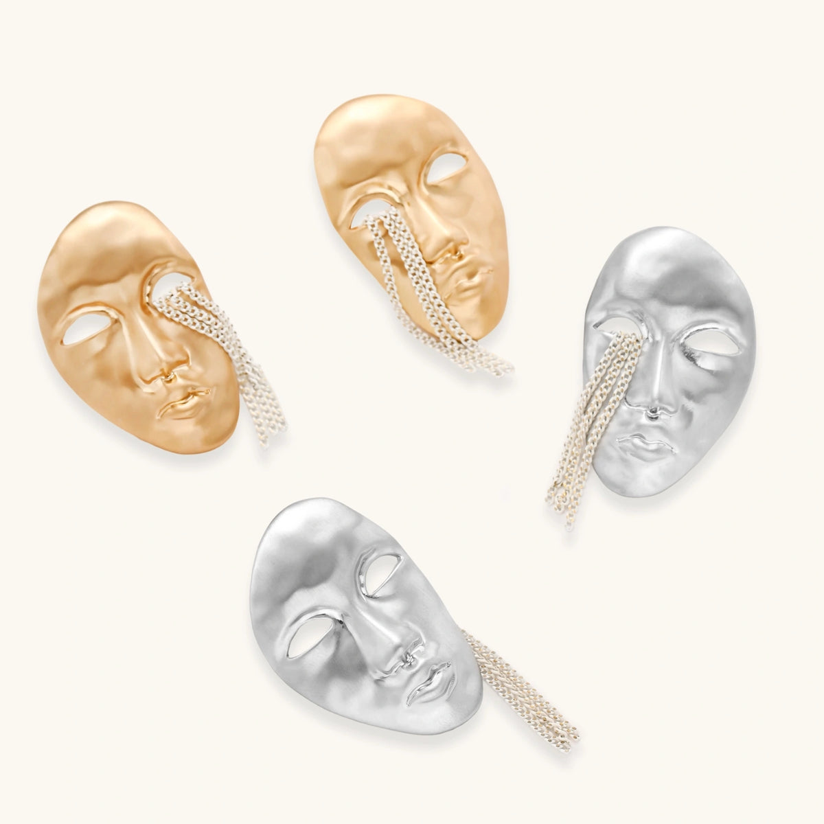 Silver face-shaped statement earrings with flowing chain tassels hanging from sculpted lips on cream background