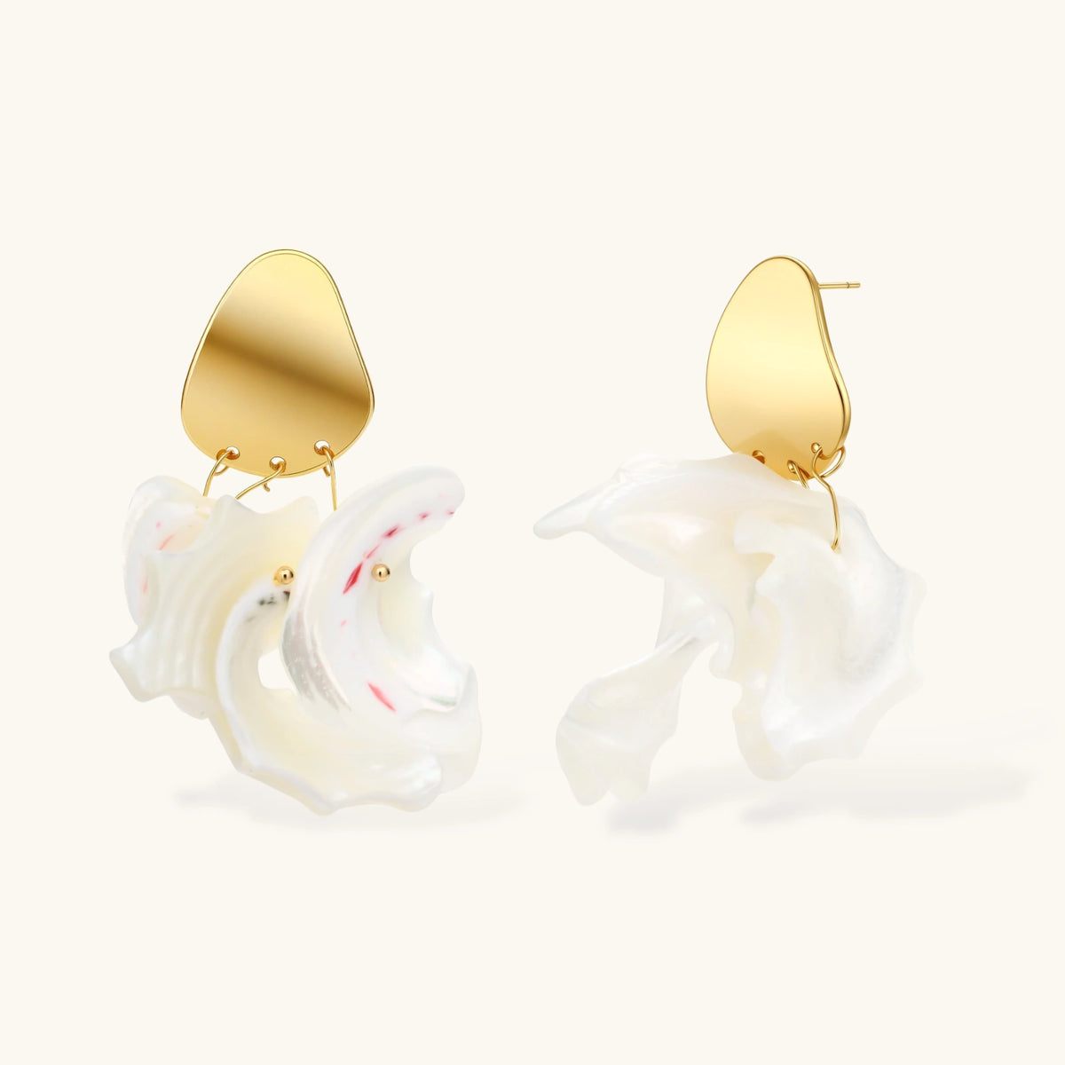 Gold-plated copper earrings with organic pebble studs and natural shell drops on cream background.
